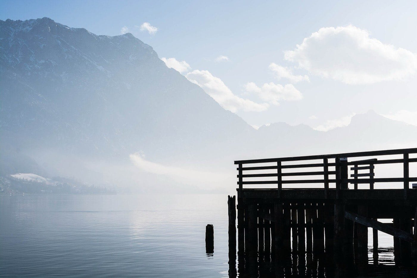 A still lake under mountains, a jetty in silhouette